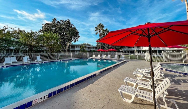 Pool with deck chairs and red umbrella